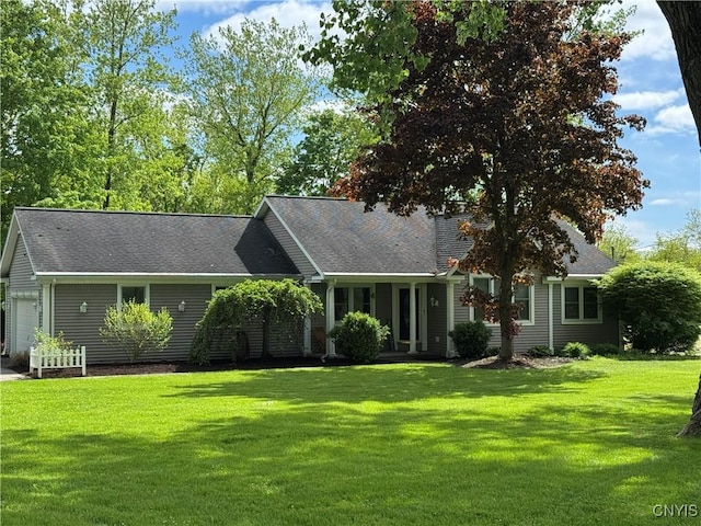 view of front of property featuring a front yard, a garage, and a shingled roof