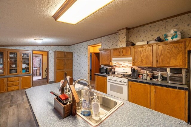 1572 County Route 6, Volney, NY 13069 - kitchen with white gas stove, wallpapered walls, brown cabinets, ornamental molding, and under cabinet range hood