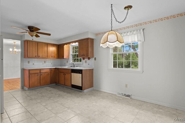 4155 Old Winding Way, Onondaga, NY 13215 - kitchen featuring white dishwasher, a chandelier, light countertops, backsplash, and brown cabinetry