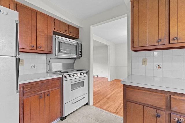 4155 Old Winding Way, Onondaga, NY 13215 - kitchen with white appliances, light countertops, brown cabinets, backsplash, and light tile patterned floors