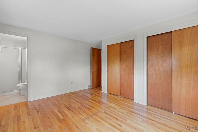 4155 Old Winding Way, Onondaga, NY 13215 - unfurnished bedroom with multiple closets, light wood-style floors, ensuite bath, and baseboards