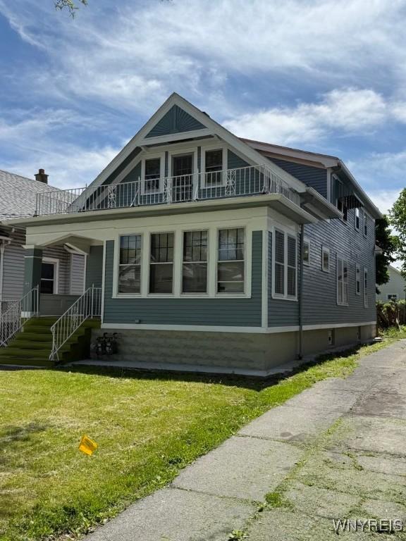 view of side of home with a balcony and a lawn