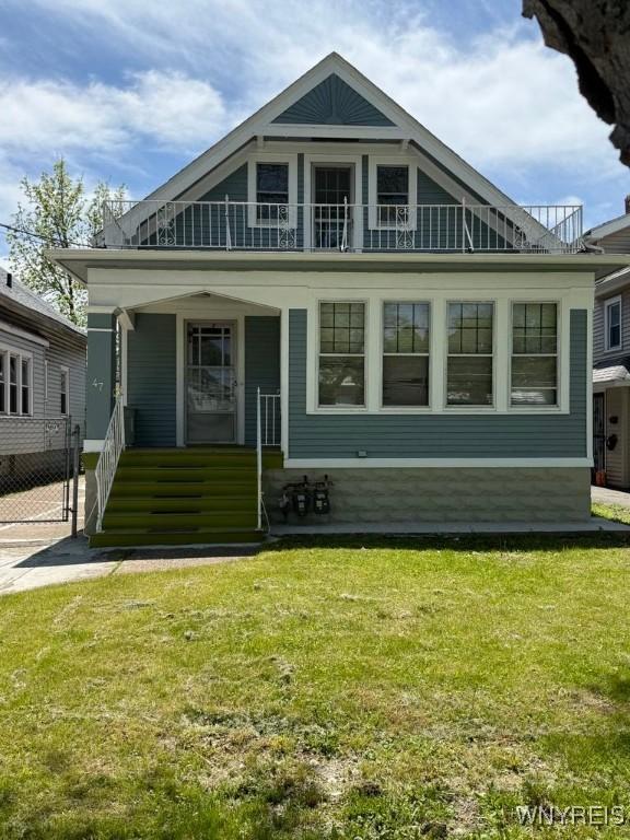 view of front of property featuring a balcony, a porch, and a front yard