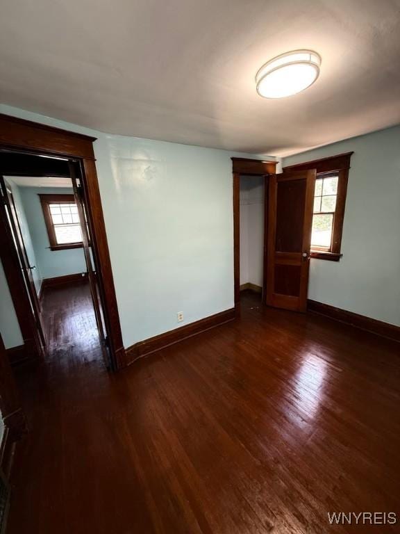 spare room with dark wood-type flooring, baseboards, and plenty of natural light