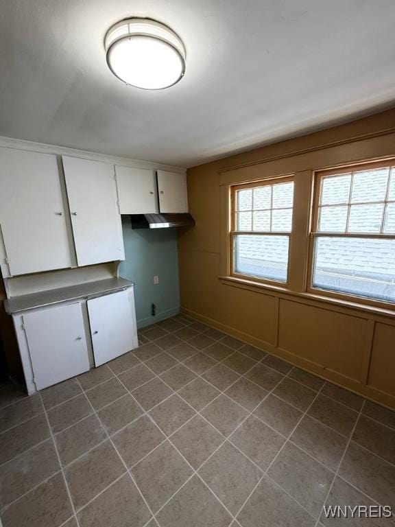 unfurnished dining area with dark tile patterned floors and baseboards