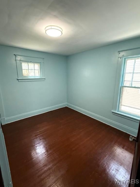 empty room with baseboards, dark wood-style floors, and healthy amount of natural light