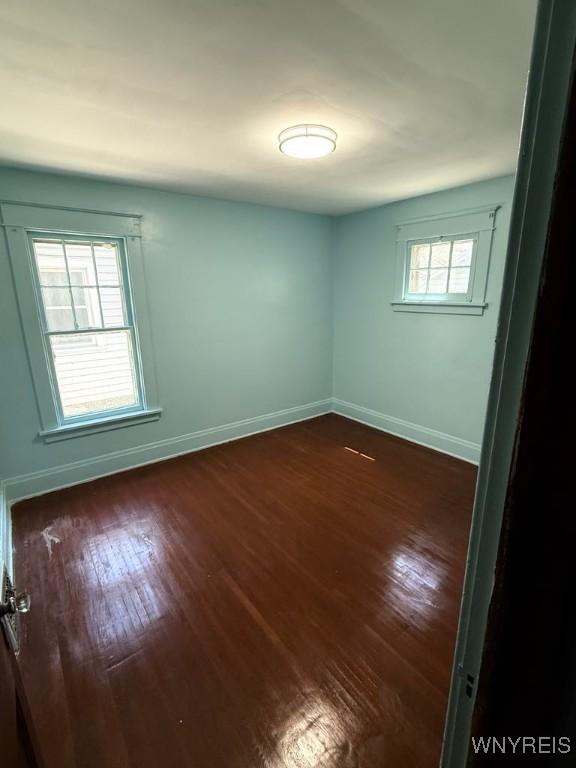 unfurnished room with dark wood-type flooring and baseboards
