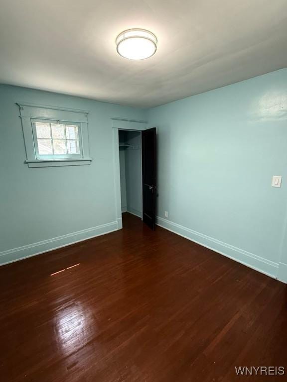 unfurnished bedroom with baseboards, a closet, and dark wood-style flooring