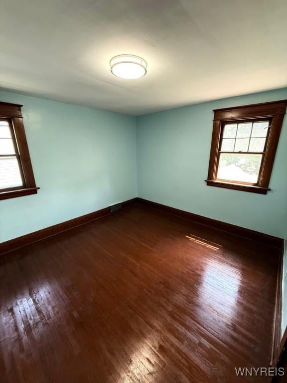 unfurnished room with plenty of natural light, dark wood-style flooring, and baseboards