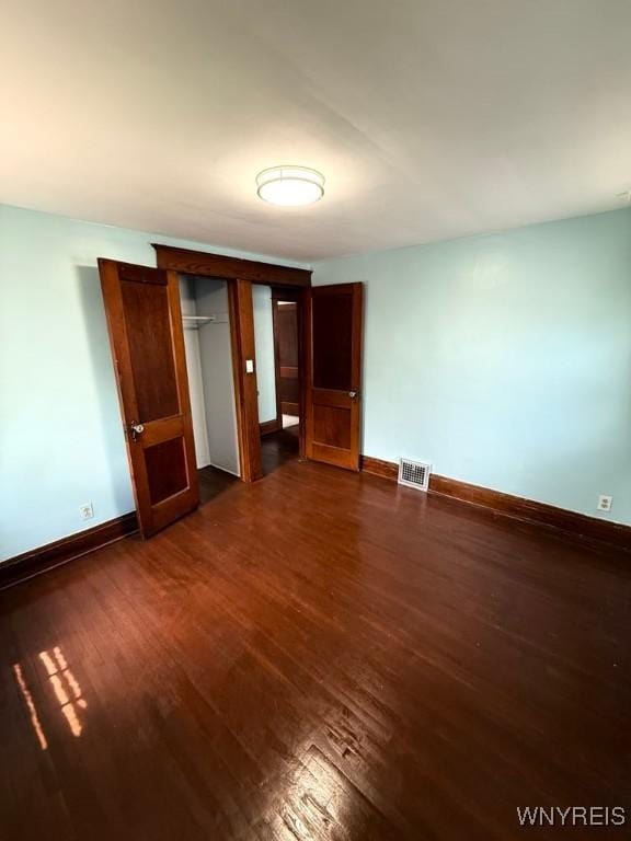 unfurnished bedroom featuring dark wood-type flooring, baseboards, and a closet