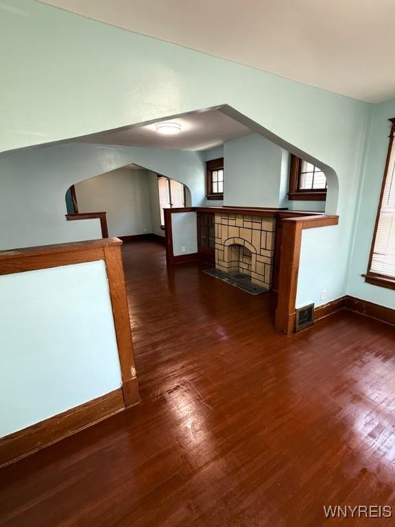 additional living space with baseboards, dark wood-style floors, and a fireplace