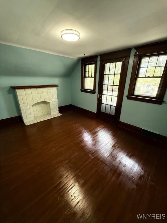 unfurnished living room with dark wood-type flooring, baseboards, and lofted ceiling