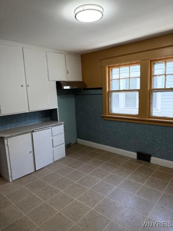 kitchen with plenty of natural light, white cabinetry, baseboards, and tile patterned floors
