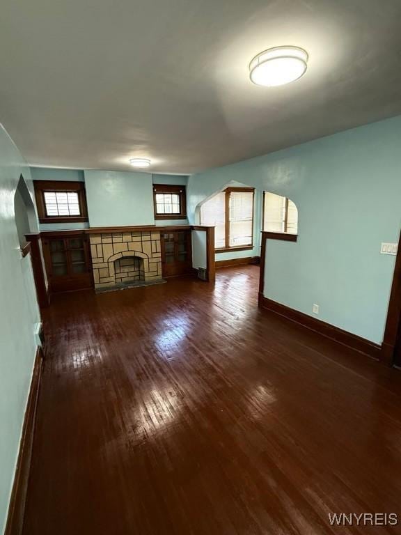 unfurnished living room featuring hardwood / wood-style flooring, baseboards, plenty of natural light, and a fireplace