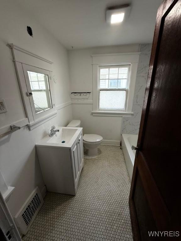 bathroom with vanity, toilet, and a tub to relax in