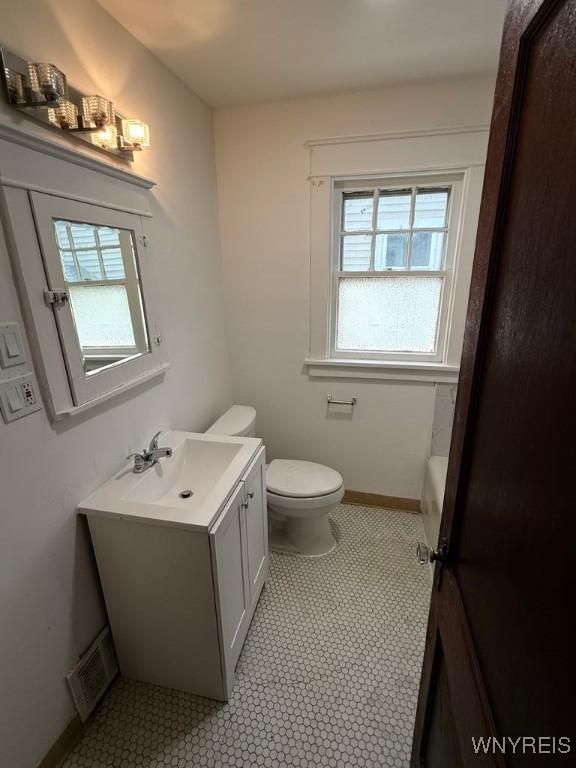bathroom featuring vanity, toilet, baseboards, and a bath