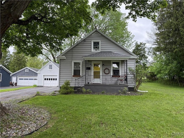 41 Young Ave, New Hartford, NY 13417 - view of front of property featuring a detached garage, covered porch, an outbuilding, a front lawn, and roof with shingles