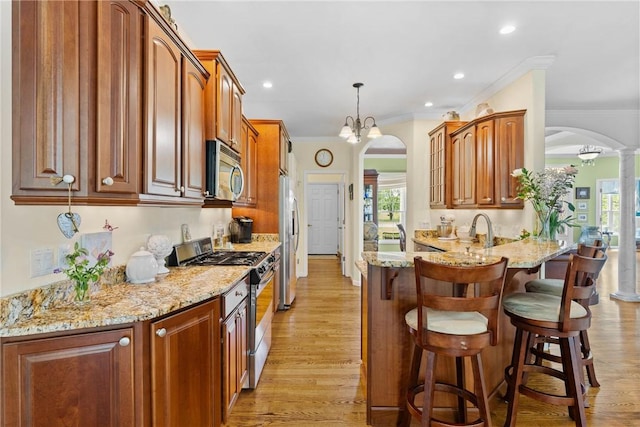 1619 Five Mile Ln Rd, Penfield, NY 14526 - kitchen featuring appliances with stainless steel finishes, arched walkways, a breakfast bar area, light stone counters, and ornamental molding