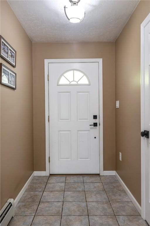 2208 Davis Rd, Corning, NY 14830 - entryway with a baseboard heating unit, light tile patterned floors, baseboards, and a textured ceiling
