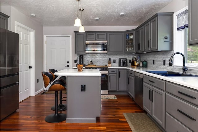 2208 Davis Rd, Corning, NY 14830 - kitchen featuring appliances with stainless steel finishes, a sink, gray cabinetry, a breakfast bar, and a kitchen island