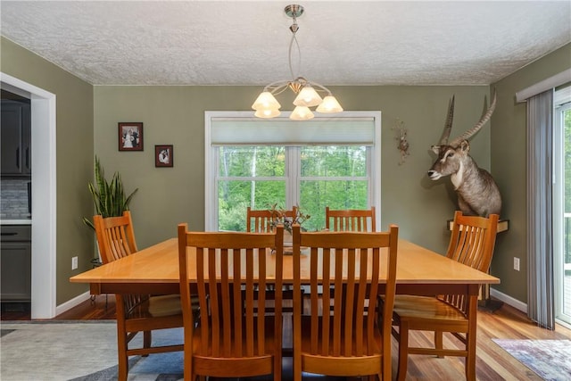 2208 Davis Rd, Corning, NY 14830 - dining area with a chandelier, a textured ceiling, wood finished floors, and baseboards