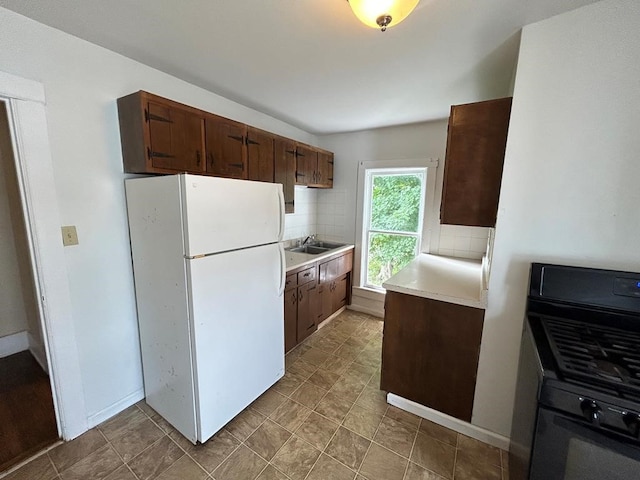 237 Scottwood Ave, Horseheads, NY 14903 - kitchen with freestanding refrigerator, a sink, light countertops, black gas stove, and tasteful backsplash