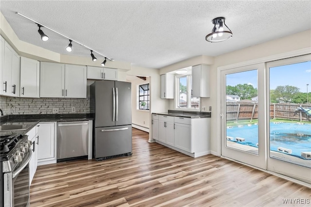307 Wadsworth Ct, Tonawanda-City, NY 14150 - kitchen with appliances with stainless steel finishes, a textured ceiling, dark countertops, baseboard heating, and backsplash