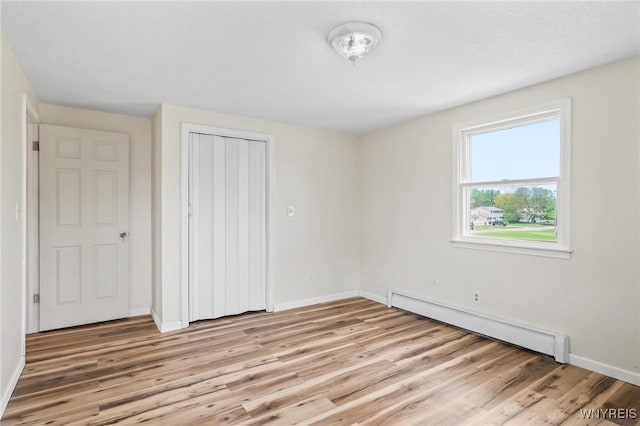 307 Wadsworth Ct, Tonawanda-City, NY 14150 - unfurnished bedroom featuring a baseboard radiator, light wood-style flooring, baseboards, and a closet