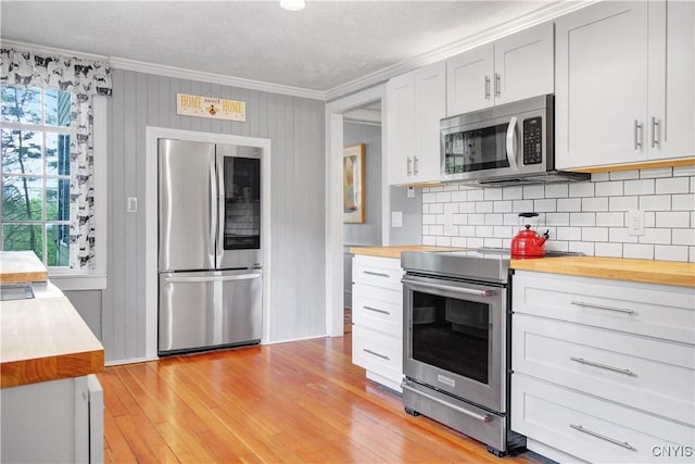 2875 W Lake Rd, Cazenovia, NY 13035 - kitchen with stainless steel appliances, butcher block countertops, ornamental molding, decorative backsplash, and light wood finished floors