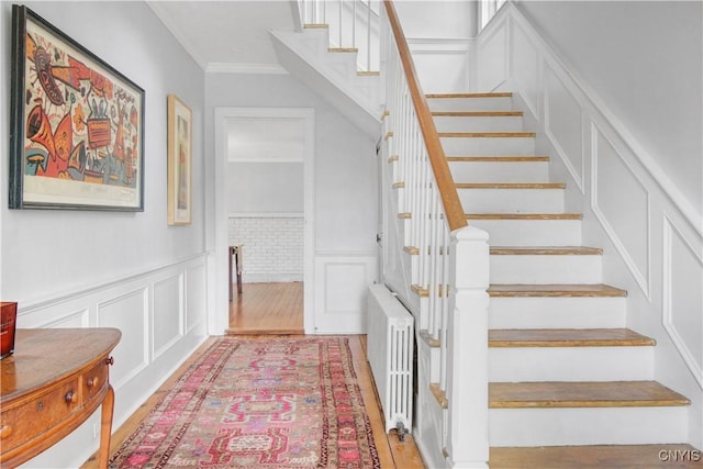 2875 W Lake Rd, Cazenovia, NY 13035 - staircase with a decorative wall, radiator, crown molding, wainscoting, and wood finished floors