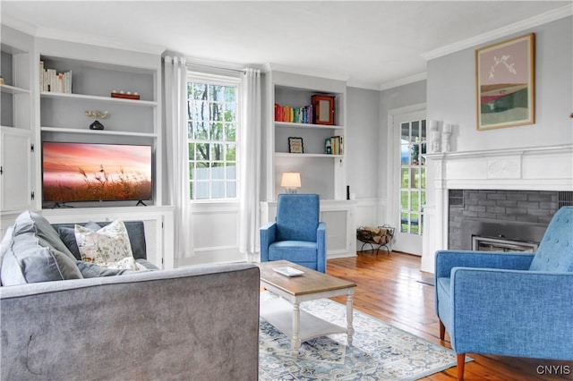 2875 W Lake Rd, Cazenovia, NY 13035 - living area with wood finished floors, built in features, a fireplace, and crown molding