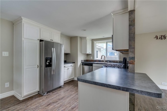 152 Leray St, Le Ray, NY 13612 - kitchen with appliances with stainless steel finishes, dark countertops, a peninsula, light wood-style flooring, and a sink
