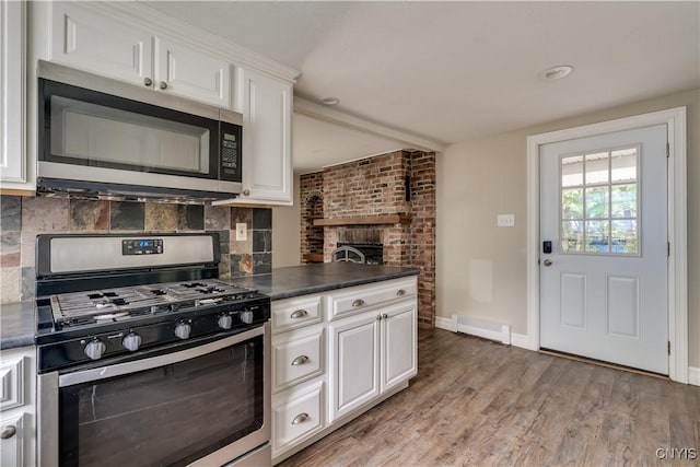 152 Leray St, Le Ray, NY 13612 - kitchen with appliances with stainless steel finishes, dark countertops, light wood-style floors, backsplash, and white cabinetry