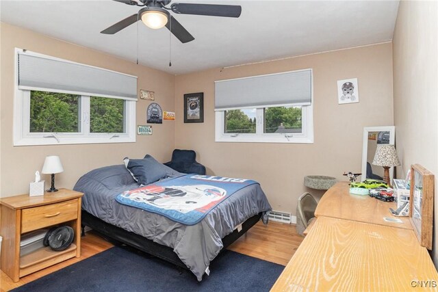 310 Wedgewood Ter, Dewitt, NY 13214 - bedroom featuring multiple windows, wood finished floors, a baseboard heating unit, and ceiling fan
