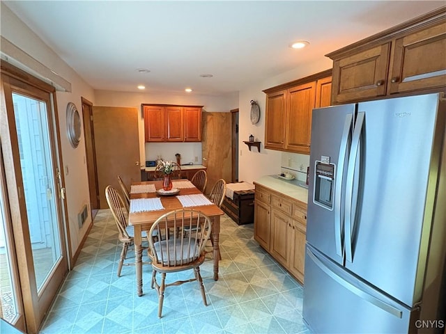 74 Eaton St, Hamilton, NY 13346 - kitchen with stainless steel refrigerator with ice dispenser, brown cabinetry, recessed lighting, and light countertops