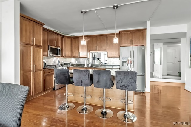 132 Lakefront Blvd Unit 403, Buffalo, NY 14202 - kitchen featuring appliances with stainless steel finishes, wood finished floors, a kitchen breakfast bar, and brown cabinetry