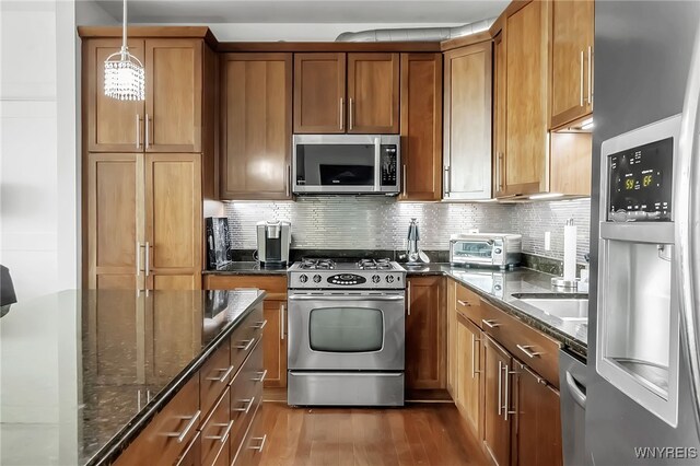 132 Lakefront Blvd Unit 403, Buffalo, NY 14202 - kitchen with stainless steel appliances, dark wood-type flooring, brown cabinetry, and dark stone counters