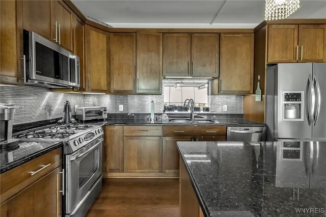 132 Lakefront Blvd Unit 403, Buffalo, NY 14202 - kitchen with stainless steel appliances, a sink, dark wood-style flooring, brown cabinetry, and dark stone counters