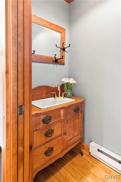 18 E Genesee St Unit 1, Skaneateles, NY 13152 - bathroom featuring a baseboard heating unit, vanity, and wood finished floors