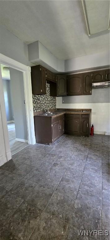 317 Portage Rd, Niagara Falls, NY 14303 - kitchen featuring dark brown cabinets, backsplash, a sink, and dark countertops