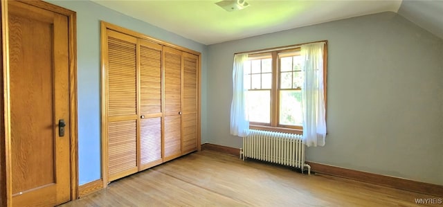 323 Portage Rd, Niagara Falls, NY 14303 - unfurnished bedroom featuring radiator heating unit, light wood finished floors, a closet, baseboards, and vaulted ceiling