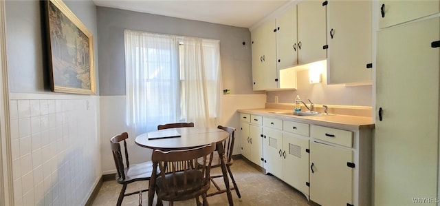 323 Portage Rd, Niagara Falls, NY 14303 - kitchen with a sink, light countertops, a wainscoted wall, tile walls, and white cabinets