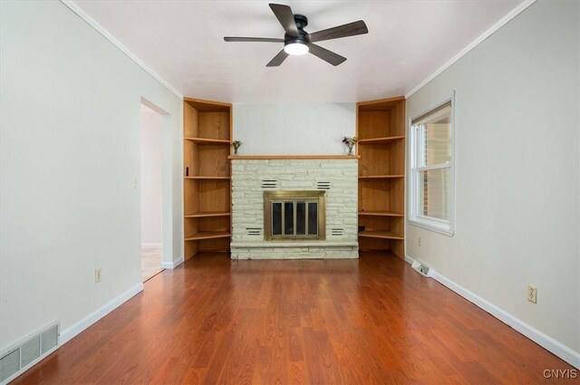 6 Viburnum Pl, New Hartford, NY 13413 - unfurnished living room with built in shelves, a ceiling fan, crown molding, a stone fireplace, and wood finished floors