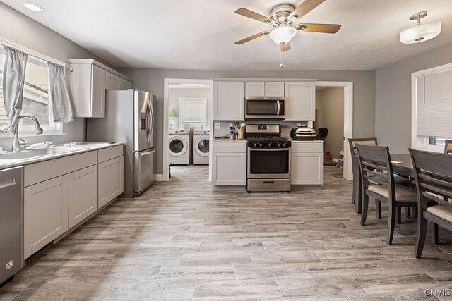 32 E 5th St, Oswego-City, NY 13126 - kitchen with stainless steel appliances, separate washer and dryer, a sink, a ceiling fan, and light countertops