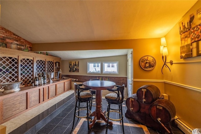 1079 State Route 49, Constantia, NY 13028 - dining area with a baseboard radiator, lofted ceiling, wainscoting, and a textured ceiling