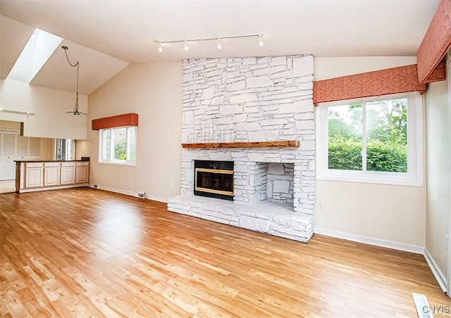 4951 Ravine Rd, Manlius, NY 13066 - unfurnished living room featuring lofted ceiling, rail lighting, wood finished floors, baseboards, and a fireplace