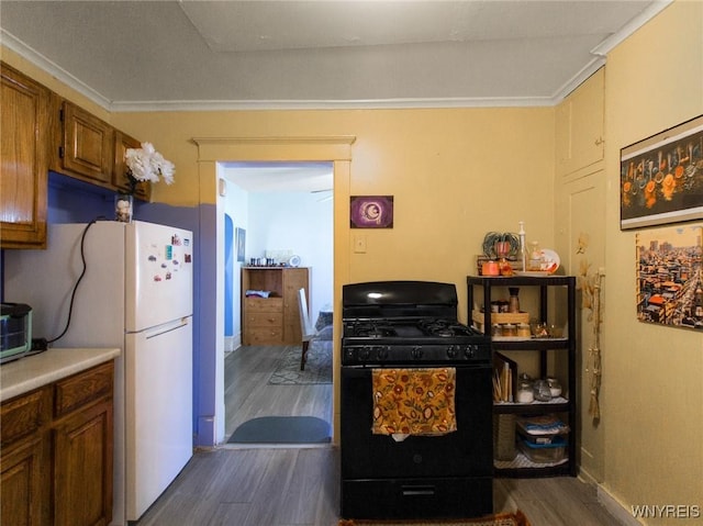 18 Rounds Ave, Buffalo, NY 14215 - kitchen with black gas range oven, dark wood-type flooring, freestanding refrigerator, brown cabinets, and crown molding