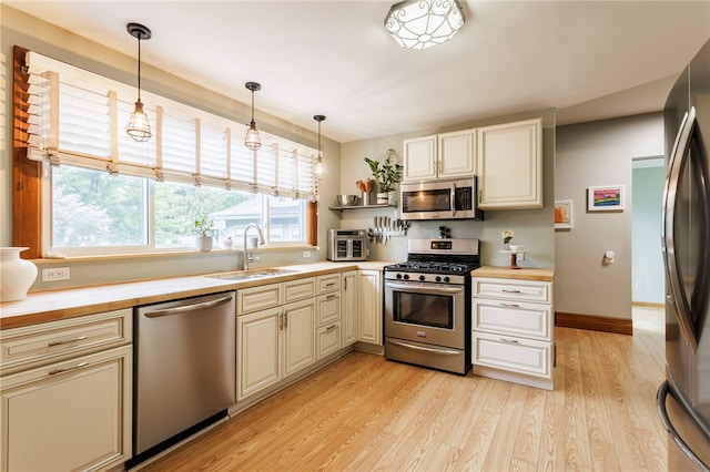 540 List Ave, Irondequoit, NY 14617 - kitchen featuring appliances with stainless steel finishes, a sink, cream cabinetry, light wood-style floors, and decorative light fixtures