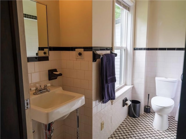 36 Pinetree Ln, Middletown, NY 12430 - bathroom featuring tile walls, toilet, wainscoting, tile patterned floors, and a sink