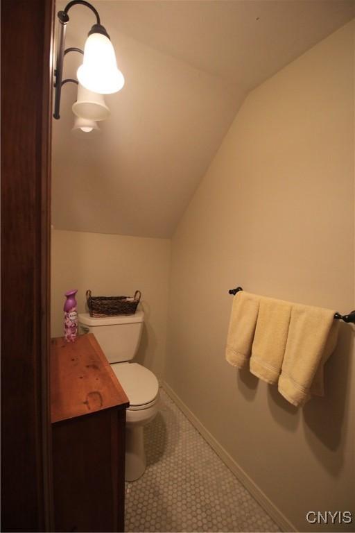 14 Fenner St, Cazenovia, NY 13035 - bathroom featuring vaulted ceiling, toilet, baseboards, and tile patterned flooring